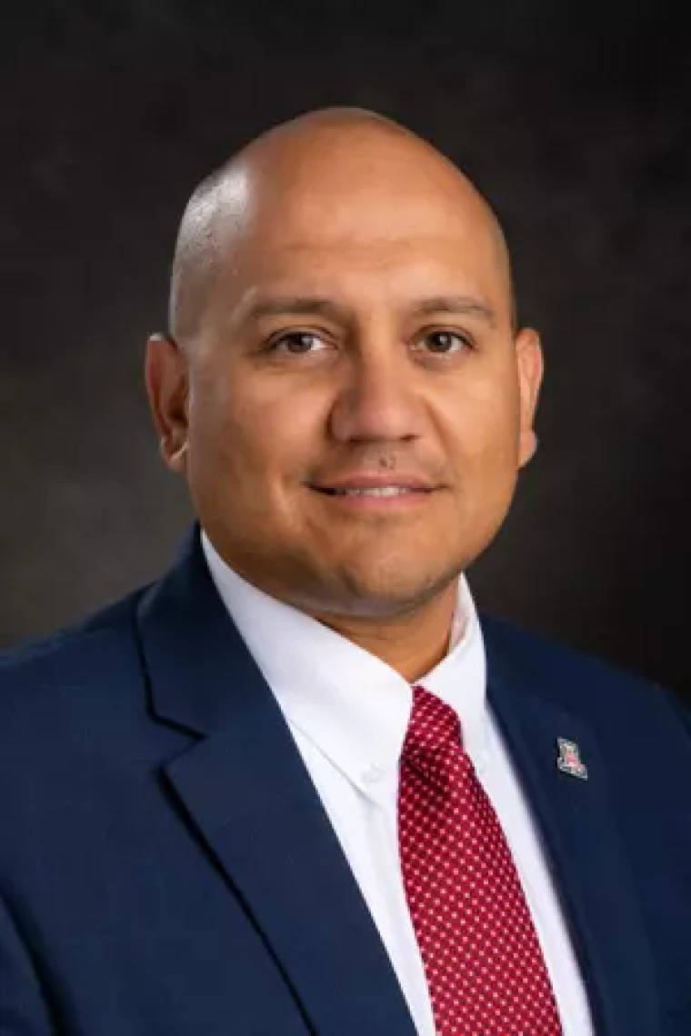headshot of mario in blue suit jacket white shirt and red tie
