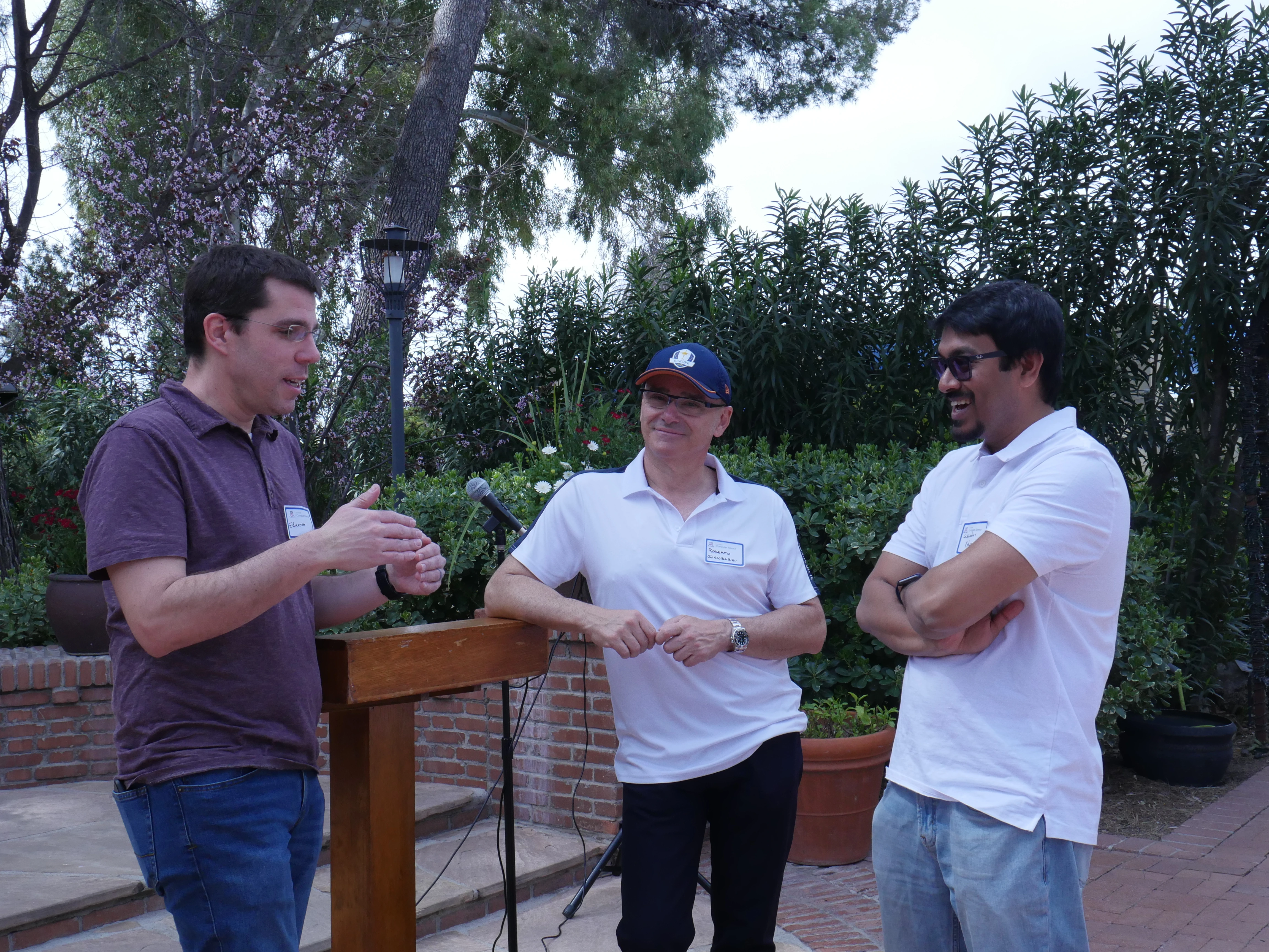 faculty discussing at a podium in a garden
